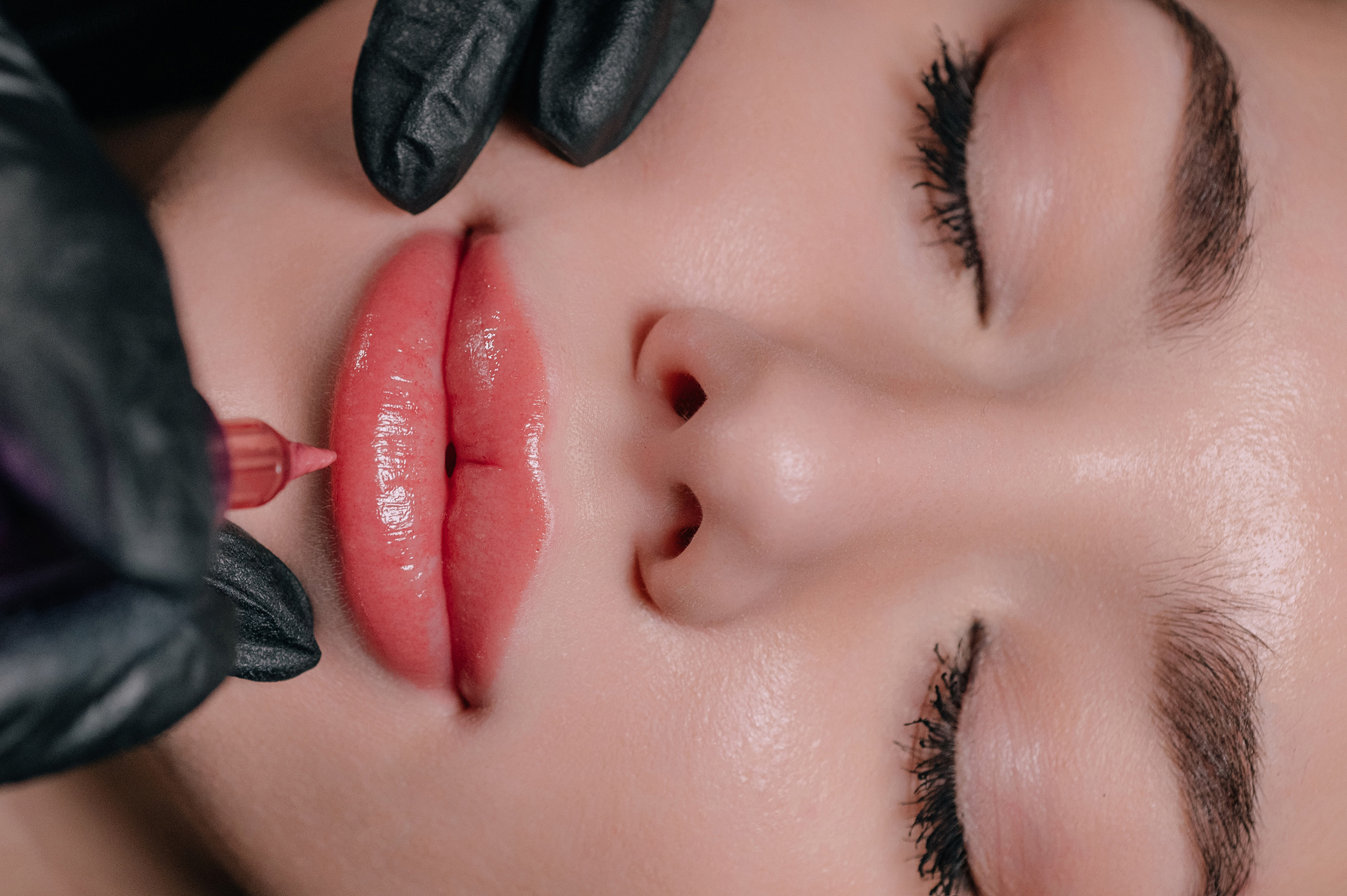 Permanent lip makeup. The cosmetologist makes the procedure of permanent makeup to the client in the salon. Close up of face.